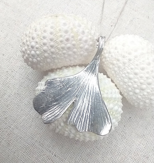 close up of detailed striations of the ginkgo leaf spread out from the stem like a delicate fish tail in this sterling silver necklace pendant