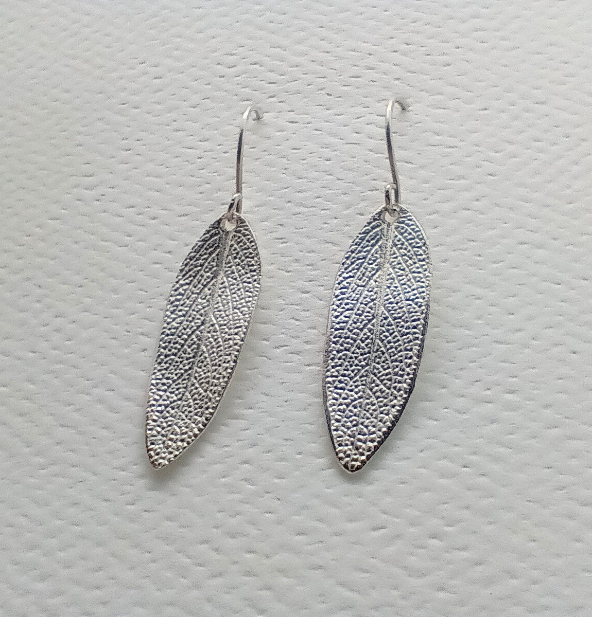 close up of the soft fine detailing of the sage leaf captured in sterling silver for this set of dangly earrings 