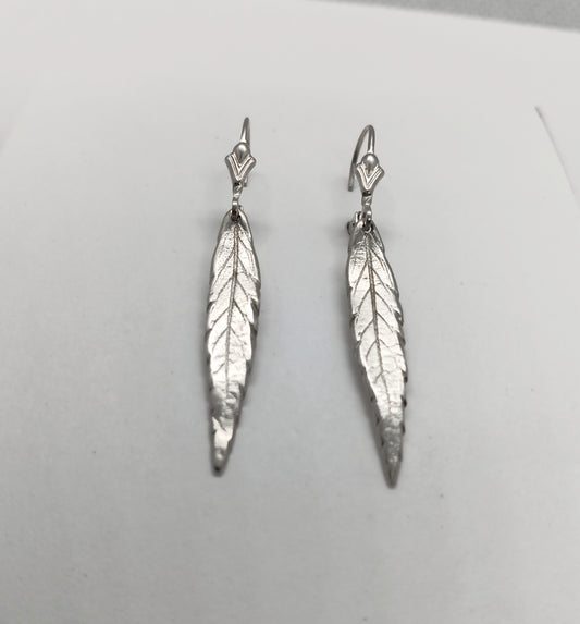 vein detail of a single lobe of a cannabis leaf is visible in sterling silver dangle as discrete earrings