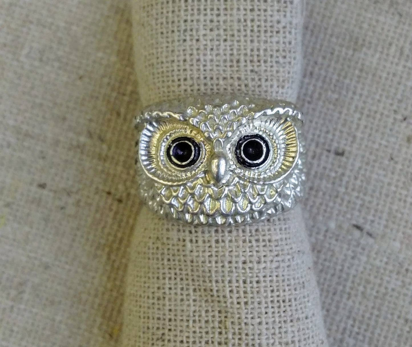 Detail of the hand carved silver wide-eyed owl head with dark stone eyes and brilliant feather detailing