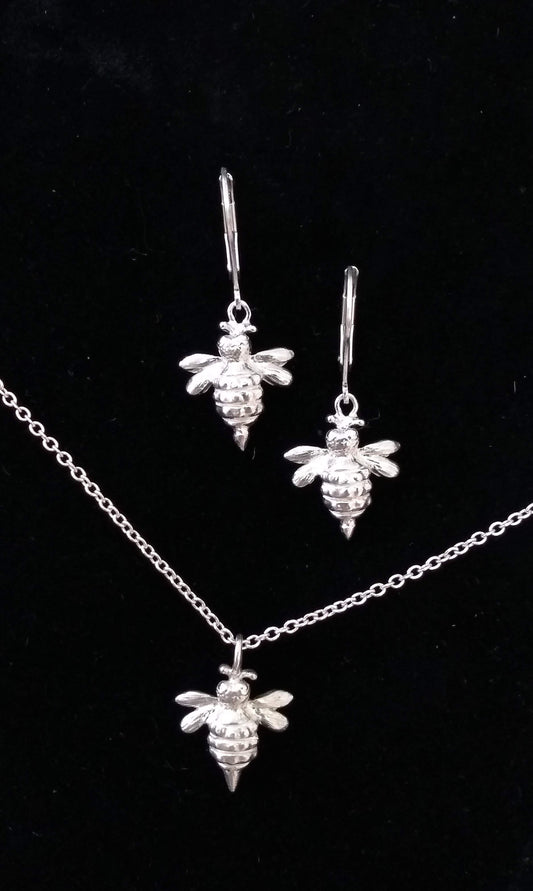 close up showing detail of bee body and wings of shiny silver pendants as earrings and necklace