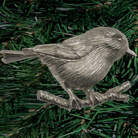 Close up showing fine feather detail of one-sided hand shiny pewter carved chickadee perched on a branch