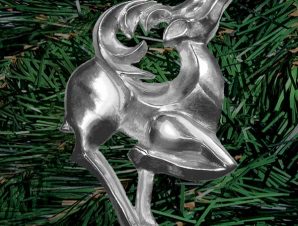 Finely detailed art-deco stylized prancing reindeer lifting its snout to the stars so its antlers dip to touch its back (palm sized, single-sided, die-cast pewter)